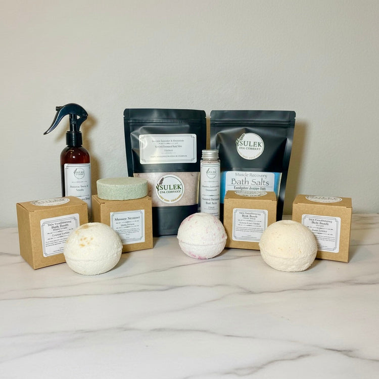 Bath and Shower collection featuring handcrafted spa essentials including bath salts, shower products, and bath bombs arranged in a calm, spa-inspired setting