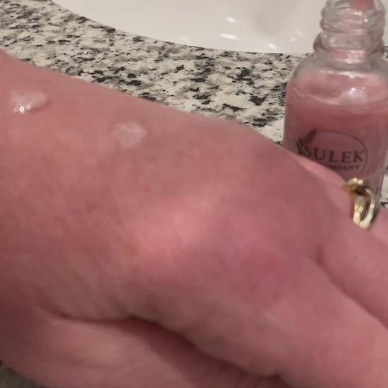 Pink shimmering body and bath oil applied to skin showing soft glow and radiant finish on arm, Sulek Spa Company