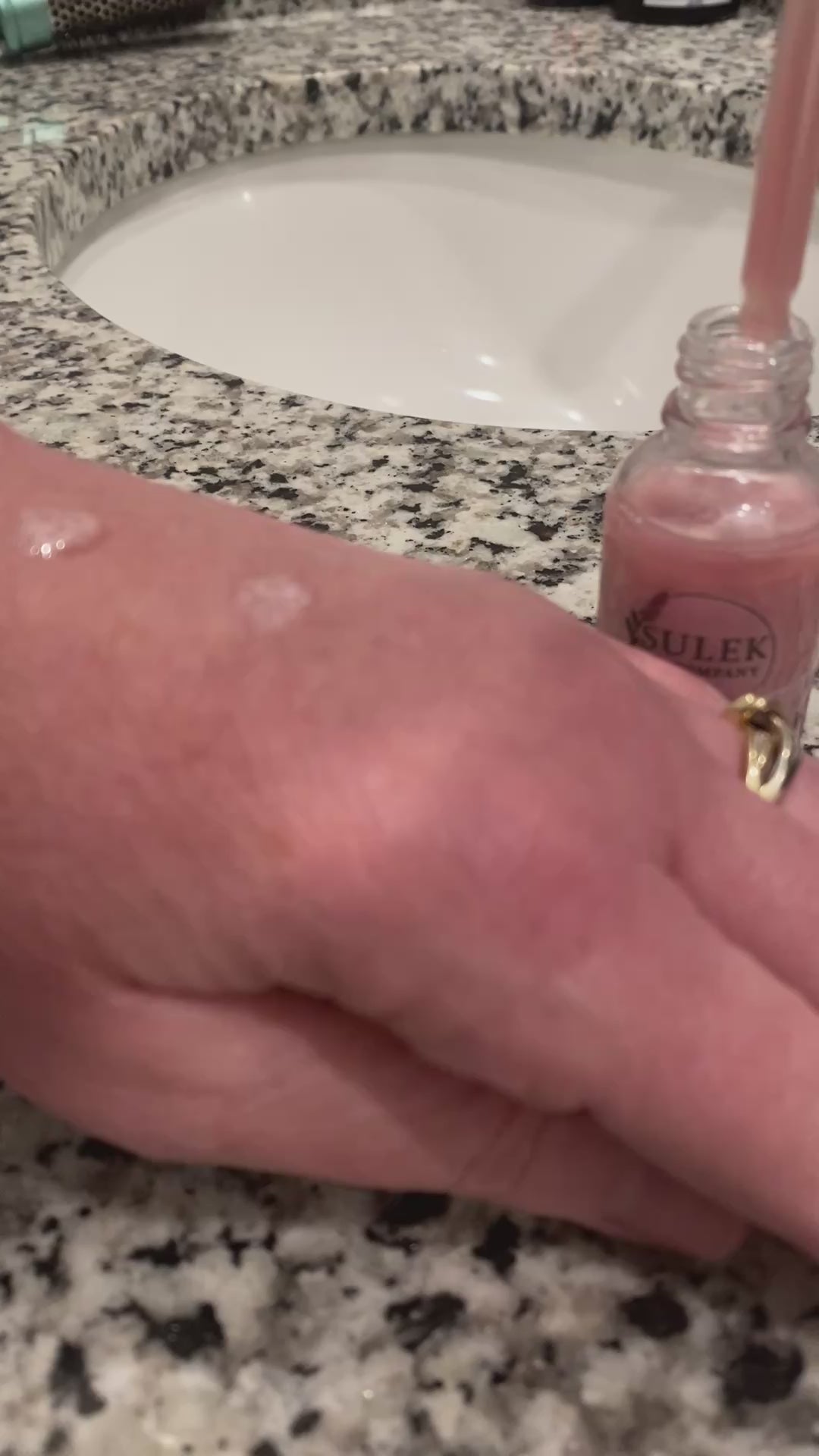 Pink shimmering body and bath oil applied to skin showing soft glow and radiant finish on arm, Sulek Spa Company