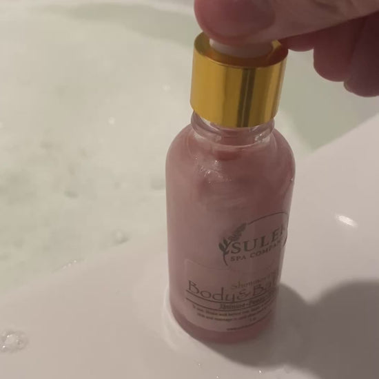 Shimmering body and bath oil bottle shown being added to bath water for a luminous, hydrated glow, Sulek Spa Company